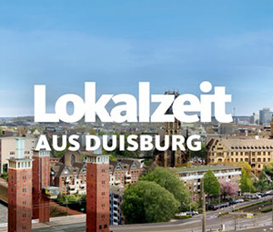 Stadtbild von Duisburg, Deutschland, mit historischen und modernen Gebäuden, Grünflächen und Straßen unter blauem Himmel. Der Text „Lokalzeit AUS DUISBURG“ ist in Weiß hervorgehoben und hebt Gemeinschaftsprojekte wie FamilienPaten hervor.