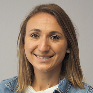 Eine Frau mit glattem, hellbraunem Haar und einem freundlichen Lächeln blickt in die Kamera. Sie trägt eine helle Jeansjacke über einem weißen Oberteil und stellt die Mitarbeitendenvertretung vor einem schlichten, hellen Hintergrund dar.